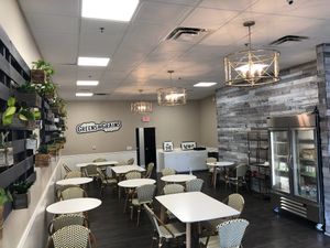 seating area with grab & go fridge stocked with cold pressed juice and fresh sides at Greens and Grains in Middletown
