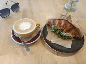 Tempeh croissant and different cats on each cappuccino. at Rohe in Tallinn