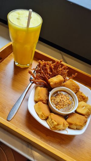 Fresh orange juice and fried tofu with satay sauce. at Minf Houze Vegan Cafe in Kuala Lumpur
