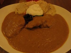 Traditional “Svíčková“ - vegetarian "meat" slices seitan with a tangy vegetable cream sauce, served with wholemeal dumplings, lime, whipped cream, and cranberries  at Maitrea in Prague