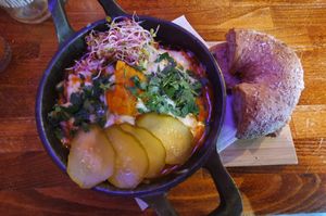 Shakshouka with baked pumpkin "egg", vegan cheese, pickled cucumber, sprouts, and garlic bread at Avocado Spot in Gdansk