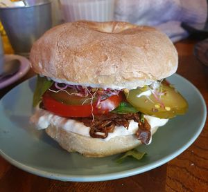 Marinated oyster mushroom (wheat bagel) with soy mayo, pickled cucumber, tomatoes, sprouts, and fresh spinach at Avocado Spot in Gdansk