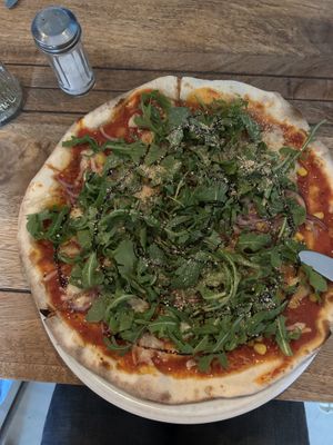 Fresh Pizza with corn, onions and arugula. Cashew Parmesan on top  at Pizzamacherei in Hamburg