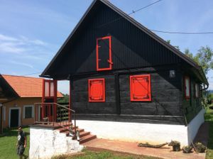 The wooden house or guest house is now painted black and red and a bit of white! at Barabrith in Donji Budacki