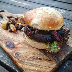 Salty and groundy BLACK burger made of black beans, onion and garlic with salad and red cabbage chips covered with teriyaki sauce. Tastes great with deep fried mushrooms as a side! at Enjoy Moon in Oslo