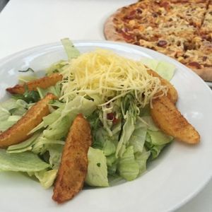 Vegan greek-style salad and a meaty pizza.  at Napfényes Restaurant & Confectionery in Budapest