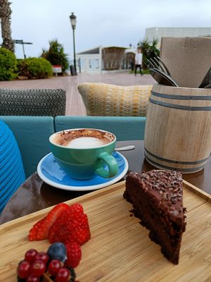 Chocolate cake and oatmilk cappuccino. Some fruit lifted along for vitamins. at Ve Cafe in Ibiza