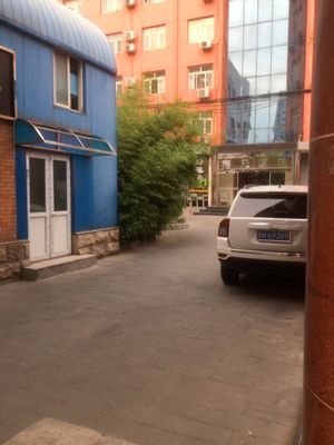in an alley way, nearing restaurant. you can see sign in the distance with the green leaf and orange arrow pointing the way. (summer 2017) at Jing Lian Zhai - Xizhimen in Beijing
