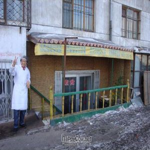 Exterior of restaurant with owner waving at Huaiye Sushi - Maybe closed in Harbin