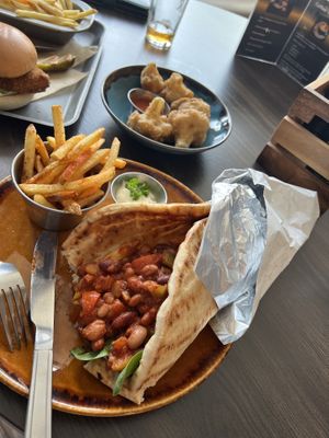 Greek pitta with 3 bean chilli, paprika fries, cauliflower fritters and ‘chicken’ burger.  at The Urban Fox in Leamington Spa