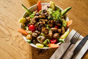 vegan Salad Meal with grilled Mushrooms: Colourful mix of green salads with mixed raw vegetables, slices of apple, roasted pumpkin and sunflower seeds, and dried cranberries at HeimWerk Altstadt in Dusseldorf