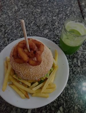Hambúrguer com anéis de cebola, batata frita e suco verde. at Taberna 32 in Porto Alegre