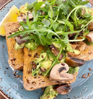 Seasoned avo on toast with mushrooms, soy seeds, rocket hat and lemon wedge 💚  at Love Brew Scarborough in Scarborough