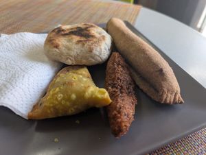 Left to right: Samosa, bake stuffed with split pea curry, accra (black eyed pea fritter), and sweet plantain encased in whole wheat. at StarLine Ital Kitchen in Roseau