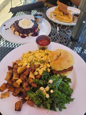 Half stack of blueberry pancakes, chicken biscuit with home fries, kale, and tofu scramble, and chicken and waffles at Cafe Sunflower in Atlanta