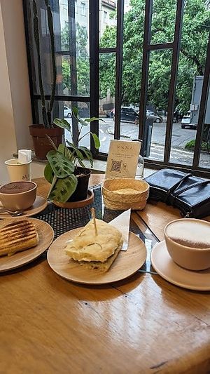Um canto do café com algumas opções do cardápio: queijo quente, foccacia e pão pizza, além de um chocolate quente e outro café at Mona Café in Belo Horizonte