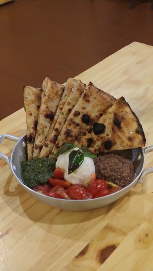 Porção de crostini servido com burrata, tomate cereja, tapenade, pesto de manjericão at Pizza Youth in Sao Paulo