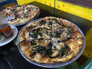 Eggplant, mushrooms, onion and spinach plus vegan cheese on my pizza. The other pizza has tomato, egglant, mushrooms and pineapple plus vegan cheese. Size is large.  at Minuteman Pizza in Uyuni