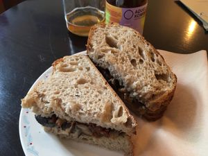 Mushroom and dry tomato sandwich, kombucha in the background at Odete Bakery in Porto