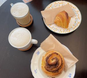 Cinnamon roll, croissant, cappuccino and iced latte (both with oats milk)  at Odete Bakery in Porto