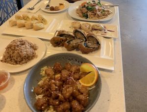 Orange chicken (front right), side of brown rice (left), seaweed quinoa roles (right), dumplings (right, 5 total) spring rolls (left), pad see ew with chicken (right back). at Salaya in Los Angeles