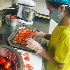 Chef Ruby's Daughter, Des, helping to decorate a strawberry shortcake. at Alice & Friends' Vegan Kitchen in Chicago