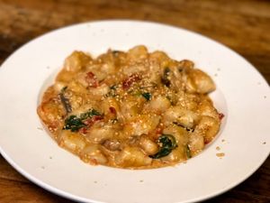 Homemade gnocchi with our creamy coconut Rose sauce with spinach , onions , garlic & roasted red peppers sprinkled with cashew Parmesan  at Paliottis Westside in Maple Ridge