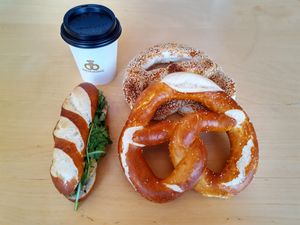 Hot beverage, avocado sandwich, sesame and plain prezel at Brezelkönig in Chur