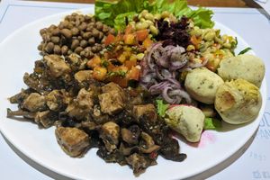 Buffet plate, including tofu with mushrooms, and vegan pão de queijo at Saude na Panela in Salvador