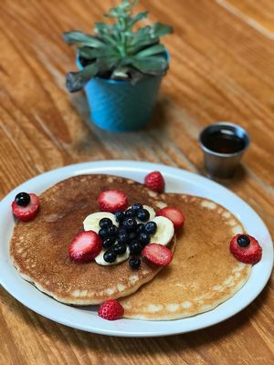 Vegan and gluten free pancakes topped with fruit and vegan butter served with maple syrup.  at Bliss Cafe in San Luis Obispo