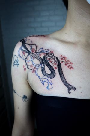 𝙄𝙂: 𝙣𝙖𝙩𝙚_𝙩𝙝𝙖𝙞𝙡𝙖𝙣𝙙 🌿Blackwork realistic snake tattoo with Sakura flowers and blue fine line wave by a blackwork tattoo artist in Chiang  at Baan Khagee Tattoo in Chiang Mai