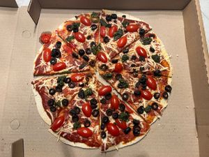 Pizza Gourmet con pesto, alcachofa, tomates cherry, salsa macha, cebolla morada y aceitunas at Goji in Saltillo