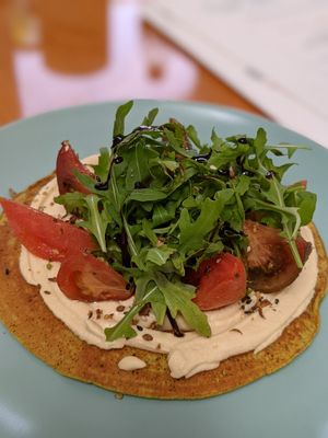 Vegan chickpea pancake with hummus, ruccola, marinated tomatoes and dukkah at Bounty Beets - Le Meridien Mina Seyahi in Dubai