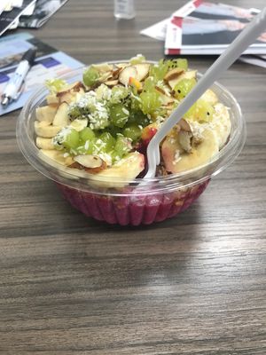 Tropical pitaya. Unbelievably good, the bottom is icy sweet deliciousness. Then the crunchy granola , and coconut flakes with fruit are the perfect combination. at Berries & Bowls in Gaithersburg