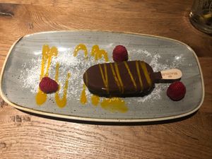 Vegan magnum from the spring menu. Served with coconut shreds, raspberries and a mango-passionfruit sauce.   at De Beren in Goes