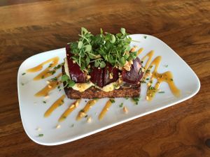 Seared stone fruit bruschetta with herbed macadamia cheese, golden balsamic reduction, hazelnuts, micro basil. at Encuentro in Oakland