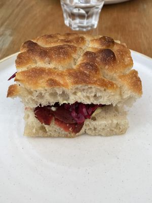 SMOKED PASTRAMI SEITAN LAYERED WITH HORSERADISH AND MUSTARD MAYONNAISE AND PICKLED RED CABBAGE ON FRESHLY BAKED FOCACCIA  at Last Light Coffee in Blackpool