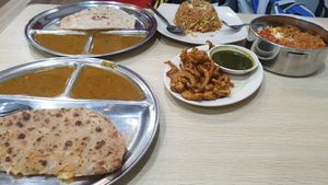 From bottom left, clockwise: aloo parantha, plain chapati, fried rice, mixed rice with sambal tofu, mutton curry and chickpeas and mixed pakoras (center) at Veg Chat in Kuala Lumpur