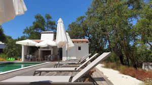 Lounge area by the pool and another seating area with a fireplace at Vegans by the Sea - Country Houses in Santiago Do Cacem