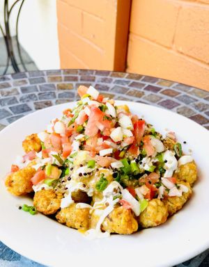 Loaded Tots: extra crispy seasoned tots with taco meat, green onion, and pico de gallo smothered in queso and sour cream   at Cozy Plum Bistro  in Sebastopol