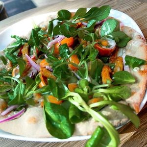 Yemayá’s pizza of spelt wheat flour with sweet & sour tofu, basil, fresh lettuce and pickled cucumber, red onions and belly peppers at Yemaya's Vegan Corner in Amsterdam
