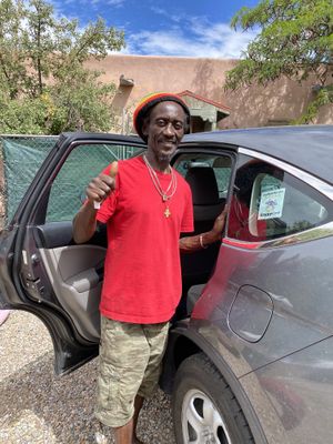 Ras putting a Happy Cow decal on his car  at Ras Rody's Jamaican Vegan  in Santa Fe