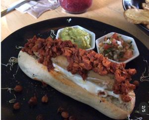 hecho en pan de levadura madre, salchicha vegana a base de soya, pepinillos. Acompañado de aguacate y pico de gallo  at Dulcinea Café Vintage in Cali
