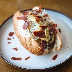 The Berliner: Fire Grilled Vegan Brat with Sauerkraut, Grilled Onions, Crispy Seitan Bacon, & Spicy Brown Mustard! at TLC Vegan Kitchen in Richardson