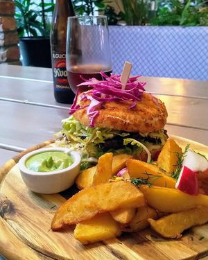 A bbq-burger with potato wedges, and kvass in the background at Kozy Eats  in Riga