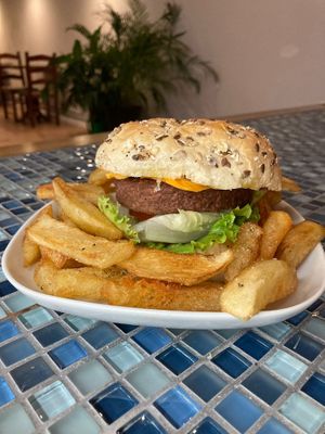 Juicy vegan burger with cheddar selfmade sauces, salat, special bun and french fries. at oValho - Vegan Snack Bar in Porto