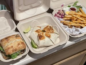 house burger (house patty & “cheese” with caramelized onion), crunchy wrap, popcorn “chikn” plate (battered & fried soy curls with fresh coleslaw & greens and sauces for di at Sprout Vegan Cafe in Kihei