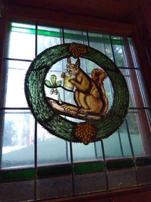 The indoors has stained glass windows including the squirrel that gives this place is name (pictured with the iconic Frankfurt cider) at Zum Eichkatzerl in Frankfurt
