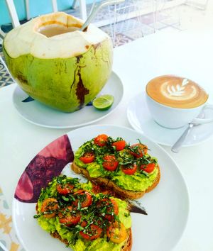 Avocado, tomato, basil toast. (Gluten-Free bread available) with cold young coconut and cappuccino (available with soya milk). at Dapur Deli in Sanur