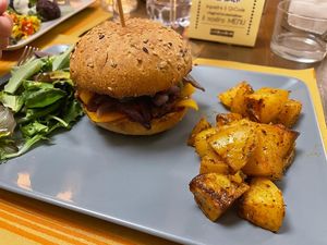 Giada burger with legumes patty, vegan cheddar, bbq sauce, peppers and caramelised onions, served with spicy baked potatoes and salad  at Laboratorio - Food. Drink. Green Cosmetics in Jesi